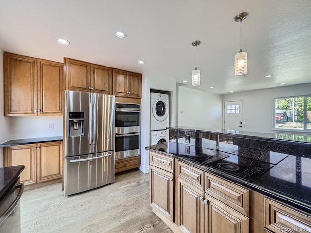 2830 E 99th Way, Thornton, CO 80229 - kitchen featuring appliances with stainless steel finishes, stacked washing machine and dryer, brown cabinetry, light wood-type flooring, and hanging light fixtures