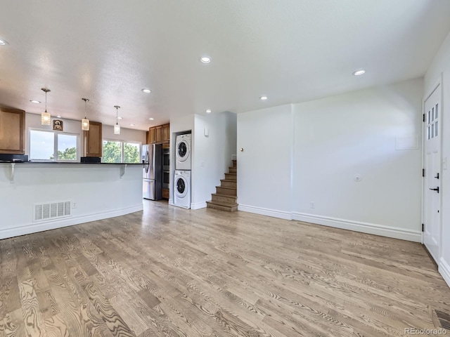 2830 E 99th Way, Thornton, CO 80229 - unfurnished living room featuring stacked washer and clothes dryer, recessed lighting, light wood-style flooring, and stairway