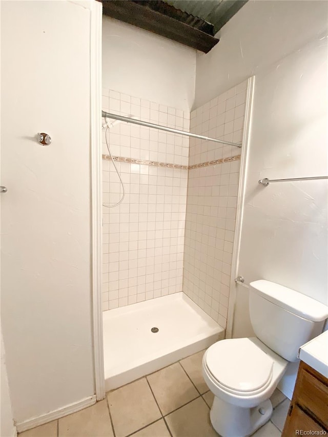 bathroom featuring vanity, a tile shower, tile patterned floors, and toilet