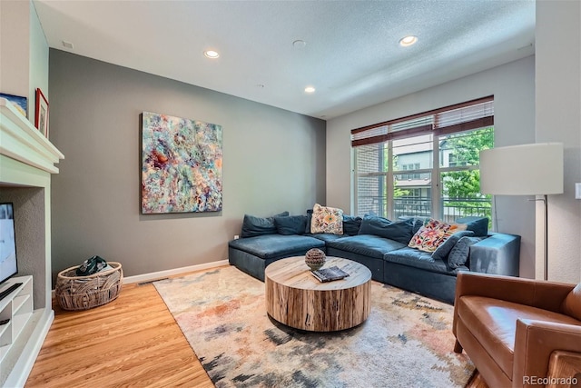 living room with recessed lighting, wood finished floors, baseboards, and a textured ceiling