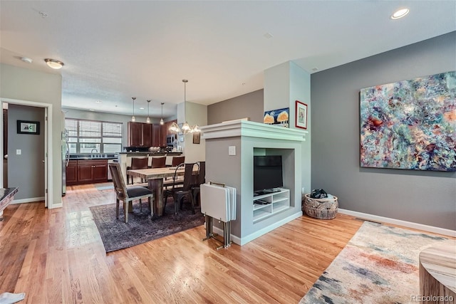 dining area featuring an inviting chandelier, light wood-style flooring, and baseboards