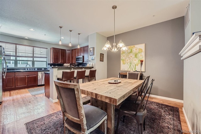 dining space with recessed lighting, light wood-type flooring, baseboards, and a chandelier