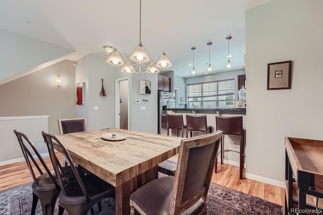 dining room with baseboards, a chandelier, and light wood finished floors