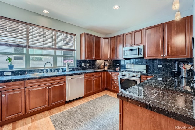 kitchen with a sink, backsplash, recessed lighting, light wood-style floors, and appliances with stainless steel finishes