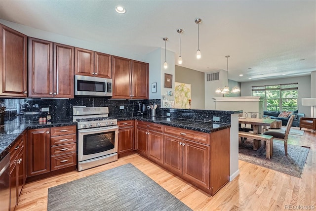 kitchen with visible vents, light wood-type flooring, a peninsula, stainless steel appliances, and tasteful backsplash