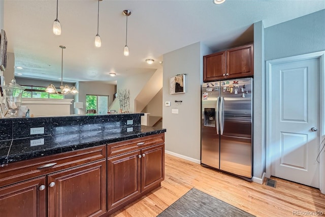 kitchen with a notable chandelier, light wood-style flooring, stainless steel fridge with ice dispenser, tile counters, and hanging light fixtures