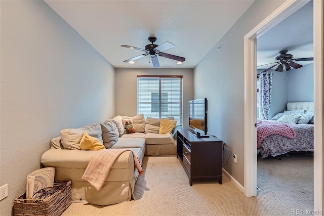 living room with light carpet, baseboards, and ceiling fan