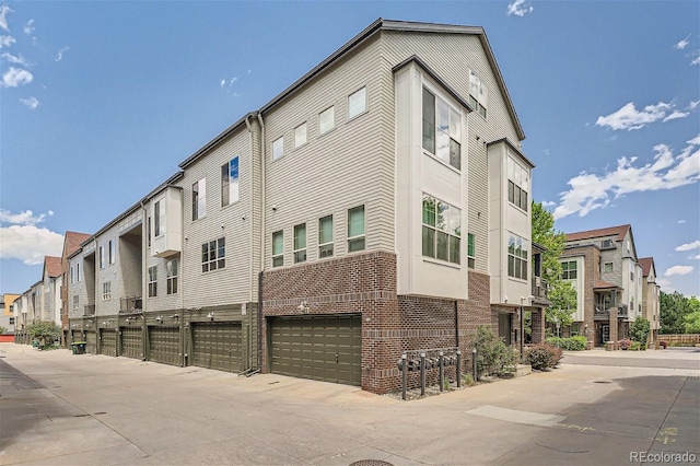 view of building exterior featuring a garage, a residential view, and concrete driveway