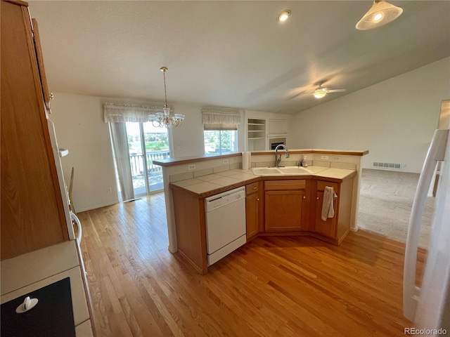 kitchen with white appliances, light wood-type flooring, ceiling fan with notable chandelier, sink, and tile countertops