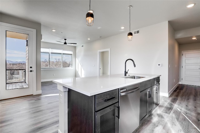 1208 N Quitman St Unit 402, Denver, CO 80204 - kitchen with stainless steel dishwasher, wood finished floors, light countertops, a kitchen island with sink, and recessed lighting