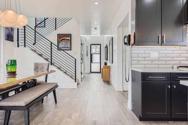 1655 Wolff St, Denver, CO 80204 - kitchen featuring dark cabinets, light countertops, light wood finished floors, decorative backsplash, and baseboards