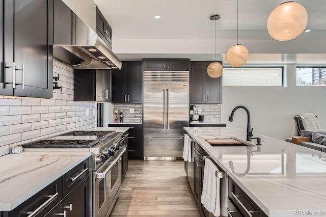 1655 Wolff St, Denver, CO 80204 - kitchen with high quality appliances, a sink, extractor fan, light stone counters, and recessed lighting