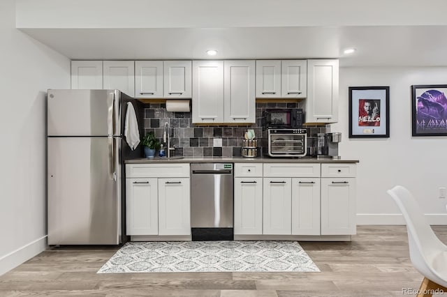 1655 Wolff St, Denver, CO 80204 - kitchen with appliances with stainless steel finishes, baseboards, decorative backsplash, white cabinets, and recessed lighting