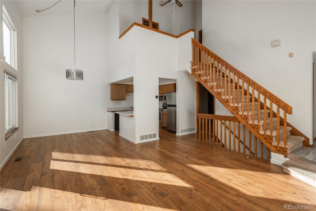 unfurnished living room with a high ceiling, hardwood / wood-style flooring, and ceiling fan