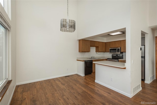 kitchen with a towering ceiling, stainless steel appliances, decorative light fixtures, and sink