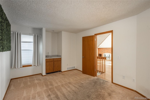 carpeted spare room with sink and a textured ceiling