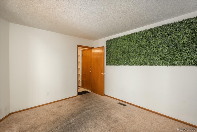 carpeted spare room featuring a textured ceiling