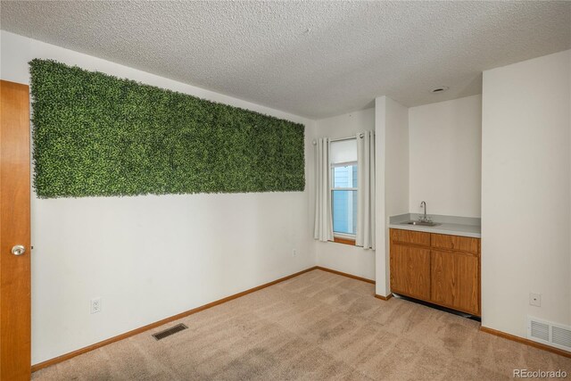 interior space featuring sink, light carpet, and a textured ceiling