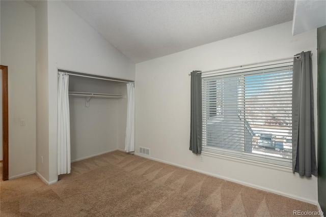 unfurnished bedroom with light carpet, vaulted ceiling, and a closet