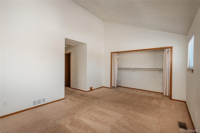 unfurnished bedroom featuring light carpet, high vaulted ceiling, and a closet