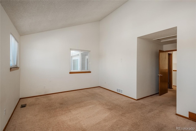 empty room featuring light carpet, vaulted ceiling, and a textured ceiling