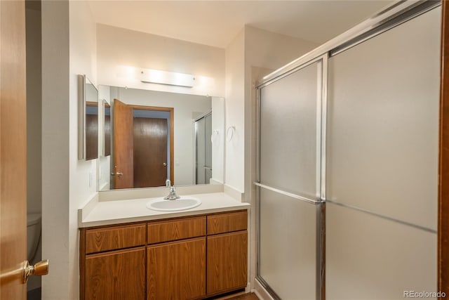 bathroom with vanity, an enclosed shower, and toilet