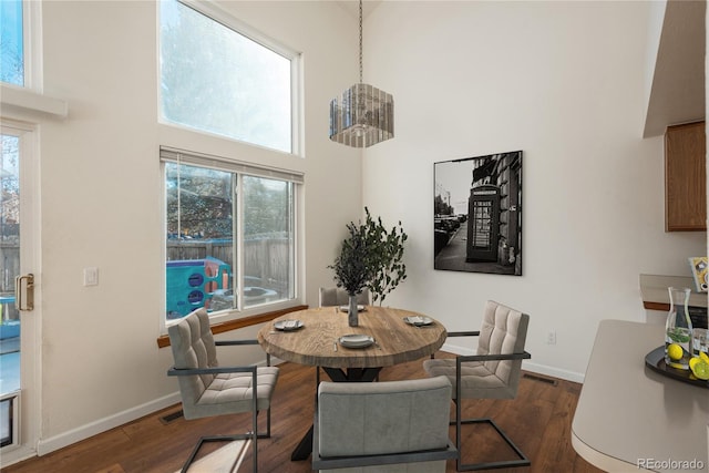 dining area featuring a high ceiling and dark wood-type flooring