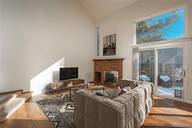 living room featuring high vaulted ceiling, hardwood / wood-style floors, and a brick fireplace