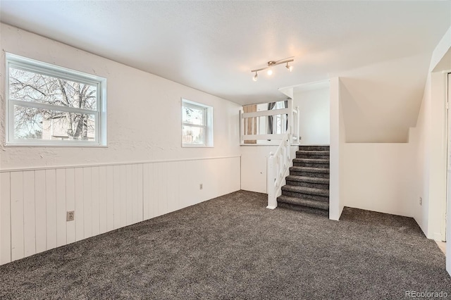 basement with rail lighting and dark colored carpet