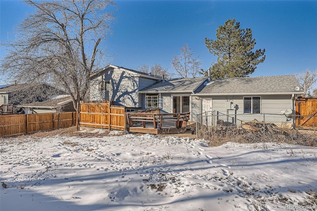 snow covered rear of property with a wooden deck