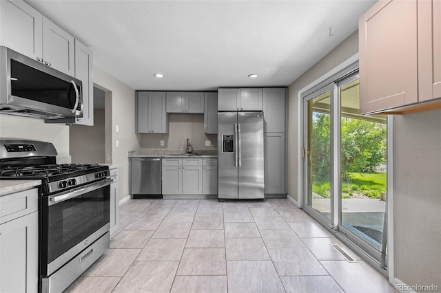 8305 Eaton Way, Arvada, CO 80003 - kitchen featuring appliances with stainless steel finishes, baseboards, gray cabinetry, recessed lighting, and light stone countertops