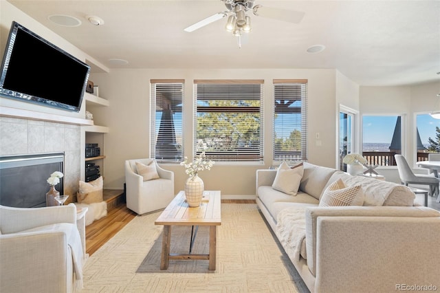 living room with a fireplace, built in shelves, a wealth of natural light, and light hardwood / wood-style floors