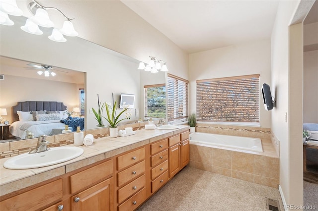 bathroom featuring ceiling fan, vanity, and tiled bath