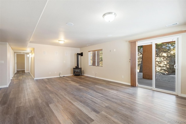 unfurnished living room featuring hardwood / wood-style floors, a wealth of natural light, and a wood stove