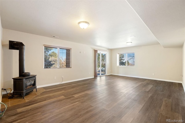 unfurnished living room with dark wood-type flooring and a wood stove