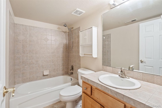 full bathroom featuring tiled shower / bath combo, vanity, a textured ceiling, and toilet