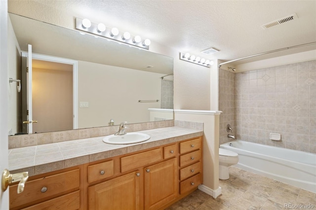 full bathroom with vanity, tiled shower / bath combo, a textured ceiling, and toilet