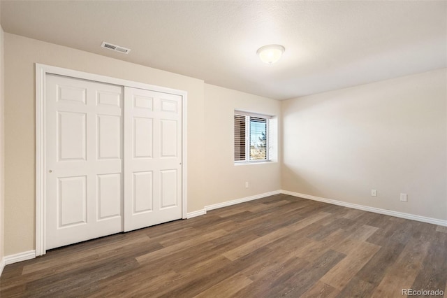 unfurnished bedroom with dark hardwood / wood-style flooring and a closet