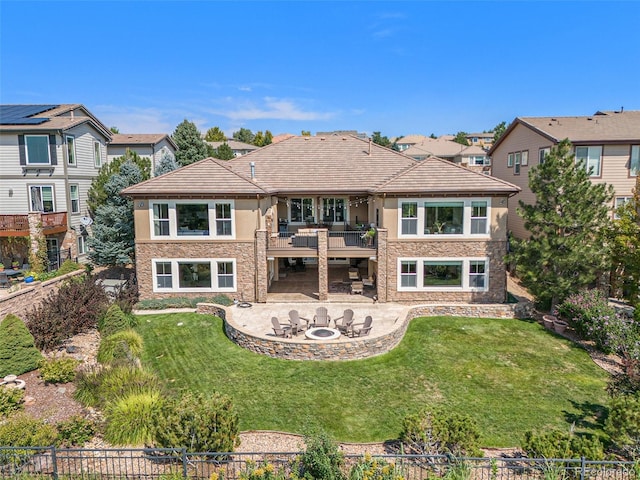 back of property featuring a balcony, a patio area, and a lawn