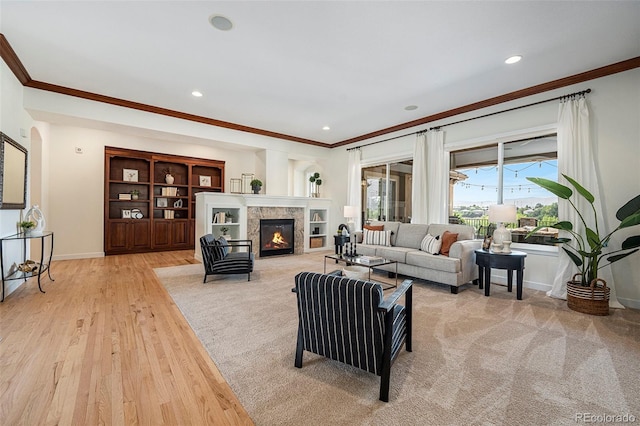 living room with a tiled fireplace, crown molding, and light hardwood / wood-style floors