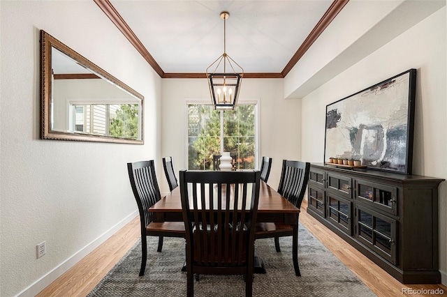 dining space featuring crown molding, wood-type flooring, and a notable chandelier