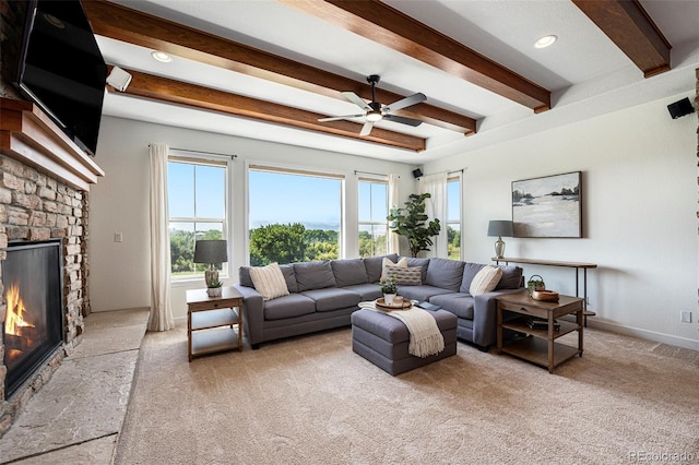 living room featuring ceiling fan, a fireplace, light colored carpet, and beamed ceiling