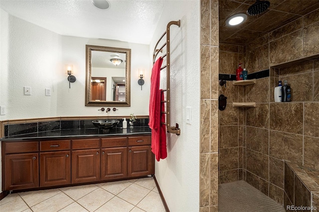 bathroom with tile patterned floors, vanity, a textured ceiling, and a tile shower