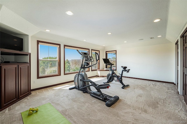 exercise room with vaulted ceiling and light colored carpet