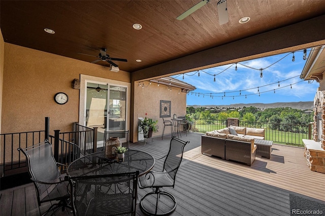 wooden deck with ceiling fan, an outdoor living space, and a mountain view