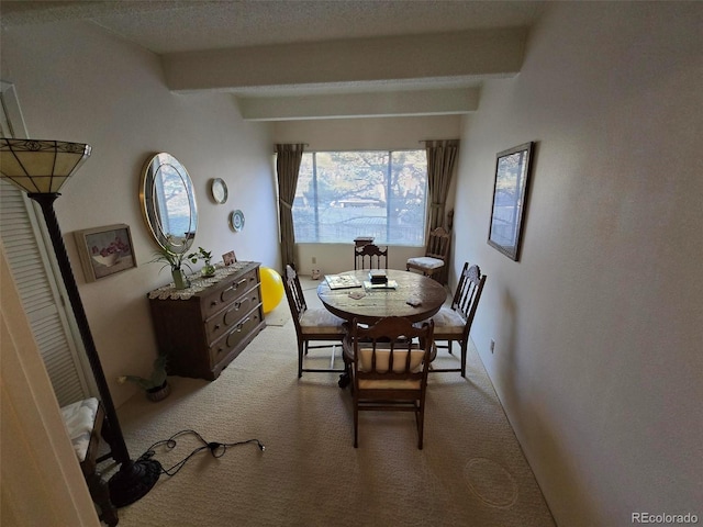 dining room featuring light carpet, a textured ceiling, and beam ceiling