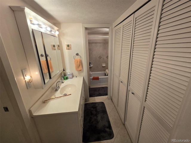 full bathroom featuring a closet, toilet, a textured ceiling, vanity, and tile patterned floors