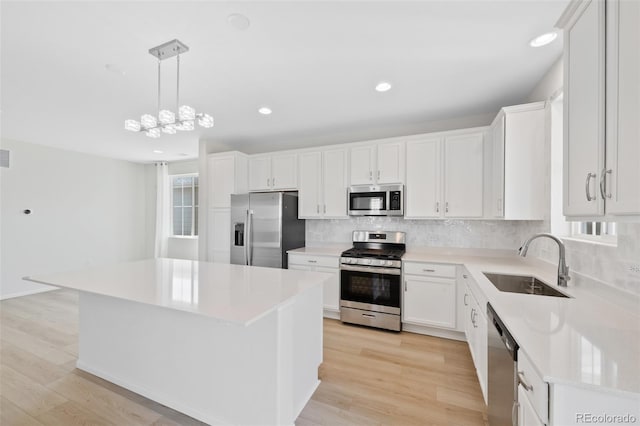 kitchen with stainless steel appliances, a sink, backsplash, recessed lighting, and white cabinetry