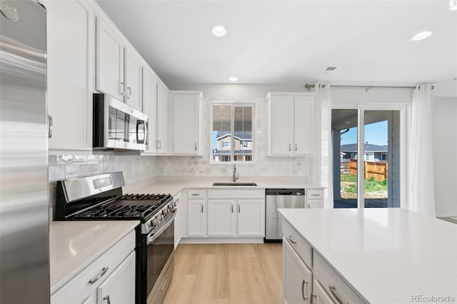 kitchen featuring stainless steel appliances, a sink, healthy amount of natural light, light wood-type flooring, and recessed lighting