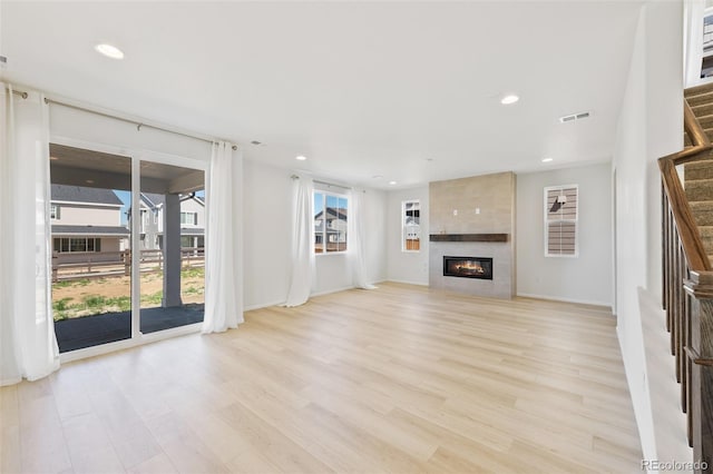 unfurnished living room with stairway, light wood finished floors, a fireplace, recessed lighting, and baseboards